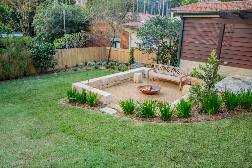 This is an example of an expansive contemporary backyard full sun garden in Sydney with a fire feature and natural stone pavers.