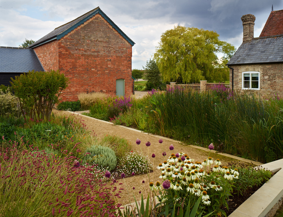 Immagine di un ampio giardino formale country esposto in pieno sole dietro casa in estate con fontane e ghiaia