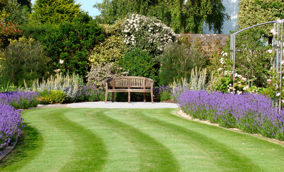 Cette image montre un jardin arrière traditionnel avec une exposition ensoleillée et un massif de fleurs.