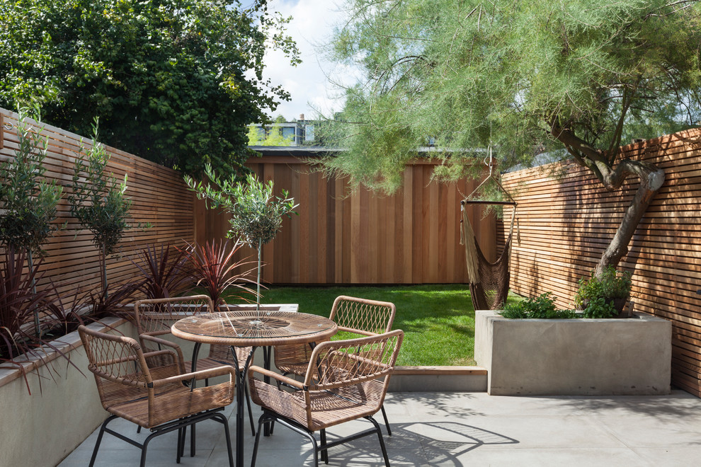 Пример оригинального дизайна: маленький участок и сад на заднем дворе в современном стиле с растениями в контейнерах и мощением тротуарной плиткой для на участке и в саду