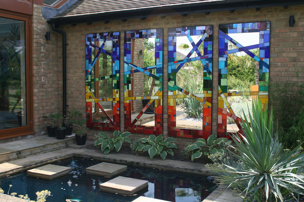 This is an example of a large eclectic back formal garden in Hertfordshire with a pond.
