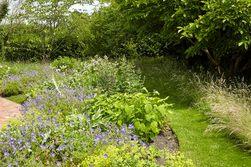 Immagine di un giardino formale country esposto a mezz'ombra di medie dimensioni e davanti casa in primavera con un ingresso o sentiero e pavimentazioni in mattoni