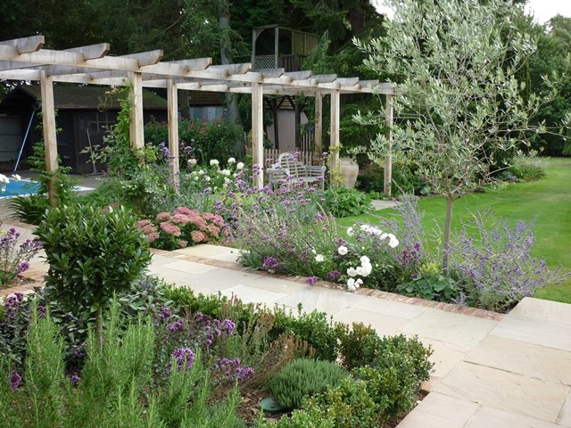 Photo of a medium sized farmhouse back garden in Hertfordshire with natural stone paving.