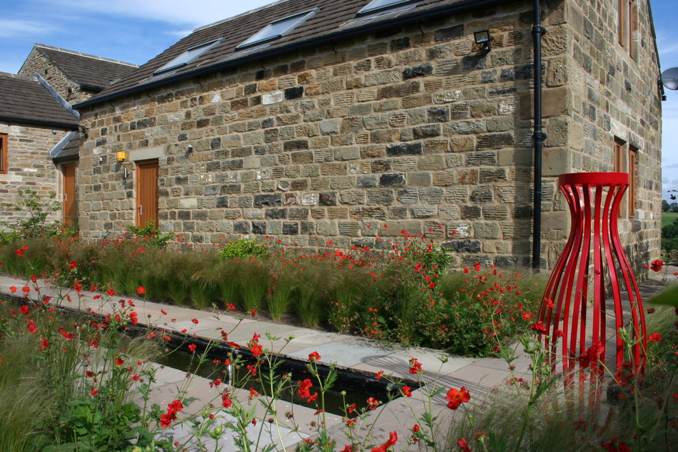 Foto de jardín clásico extra grande en verano en patio lateral con fuente, exposición total al sol y adoquines de piedra natural