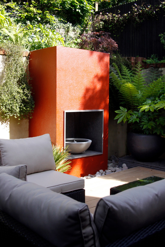 Immagine di un piccolo giardino formale minimalista esposto a mezz'ombra dietro casa con un caminetto e pedane