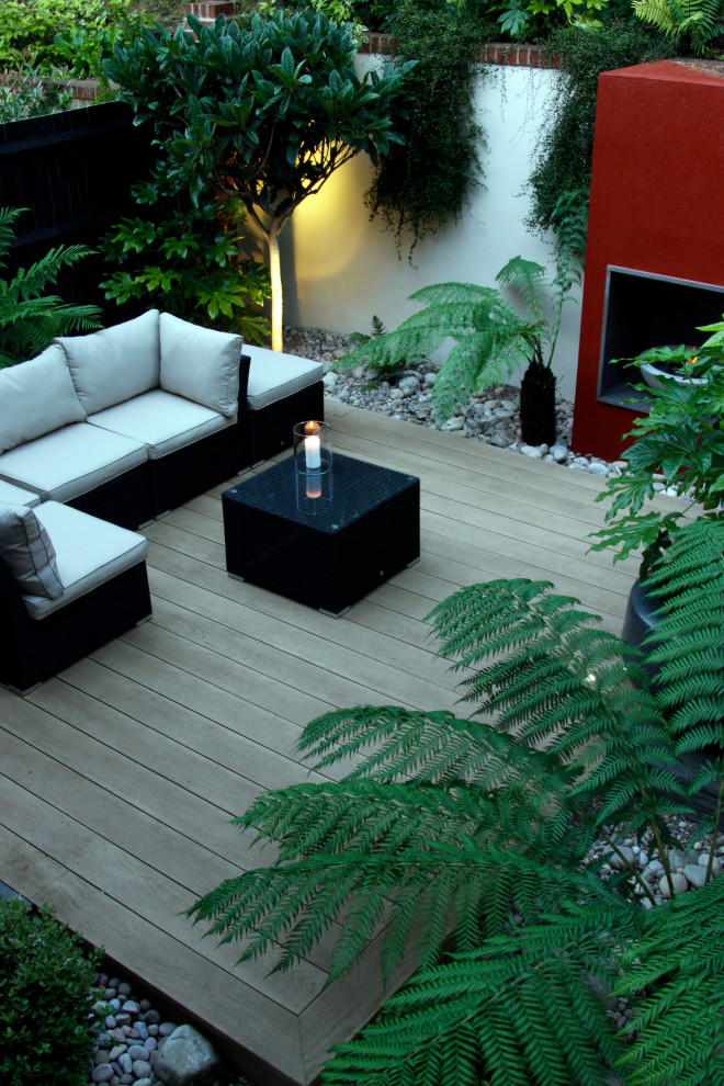 Design ideas for a small modern back formal partial sun garden in Surrey with a fireplace and decking.