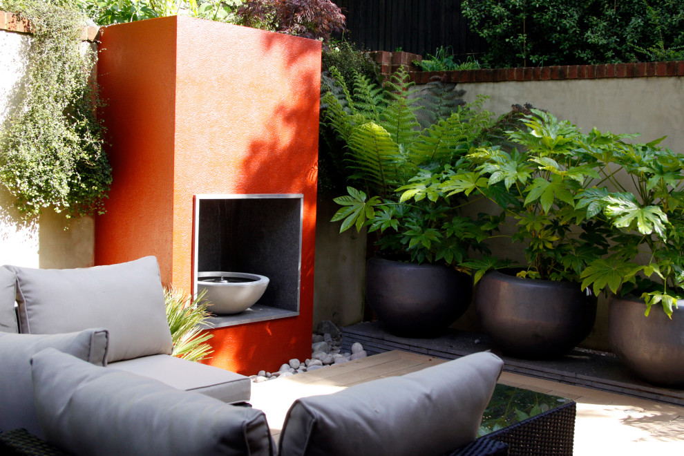 Esempio di un piccolo giardino formale minimalista esposto a mezz'ombra dietro casa con un caminetto e pedane