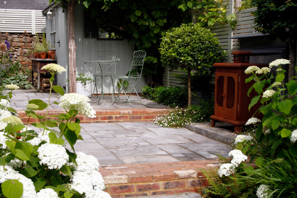 Geometrischer, Kleiner, Halbschattiger Eklektischer Gartenkamin im Sommer, hinter dem Haus mit Natursteinplatten in Kent