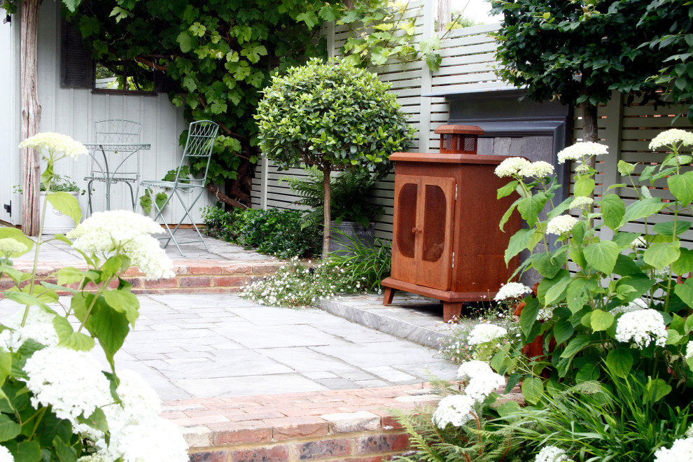 Geometrischer, Kleiner, Halbschattiger Stilmix Gartenkamin im Sommer, hinter dem Haus mit Natursteinplatten in Kent