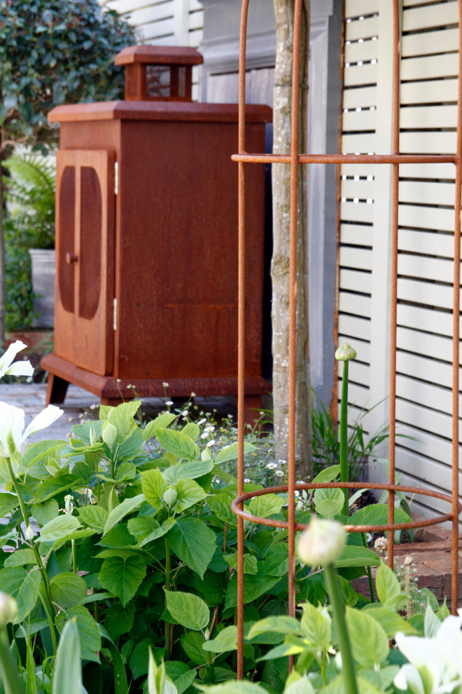 Aménagement d'un petit jardin à la française arrière éclectique l'été avec une cheminée, une exposition partiellement ombragée et des pavés en pierre naturelle.