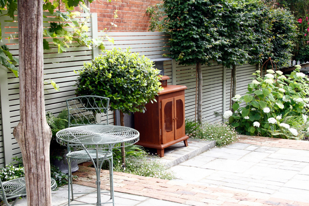 Geometrischer, Kleiner, Halbschattiger Stilmix Gartenkamin im Sommer, hinter dem Haus mit Natursteinplatten in Kent