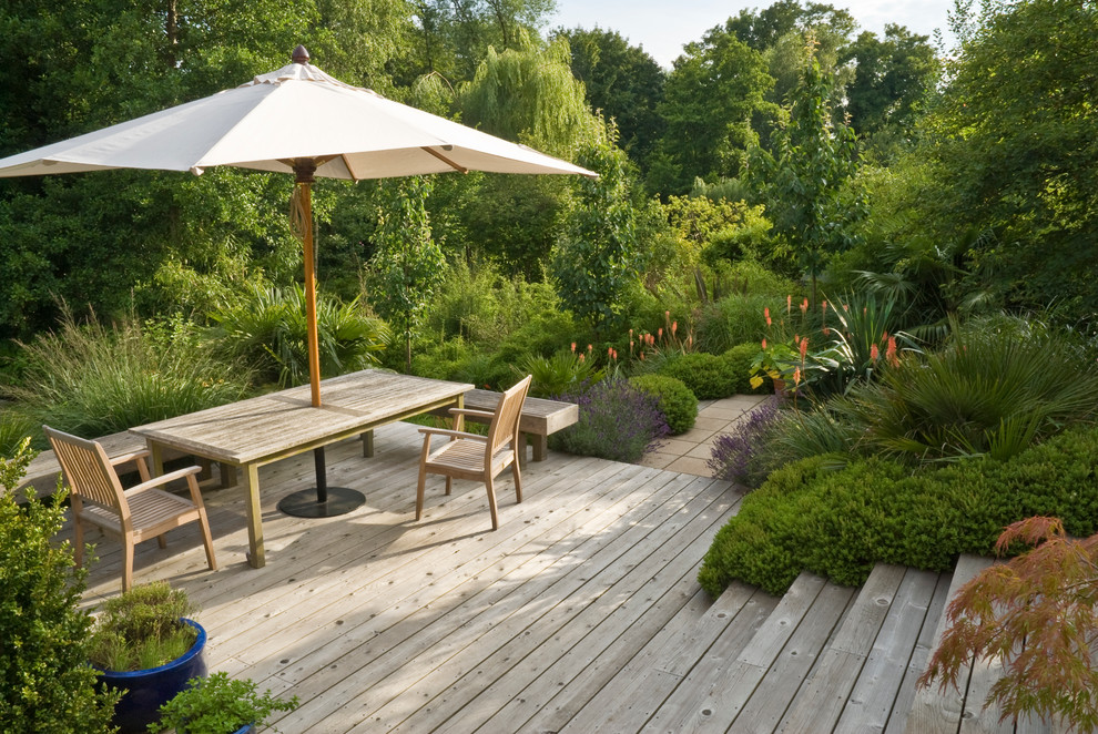 Design ideas for a mid-sized modern partial sun hillside landscaping in Sussex with decking for summer.