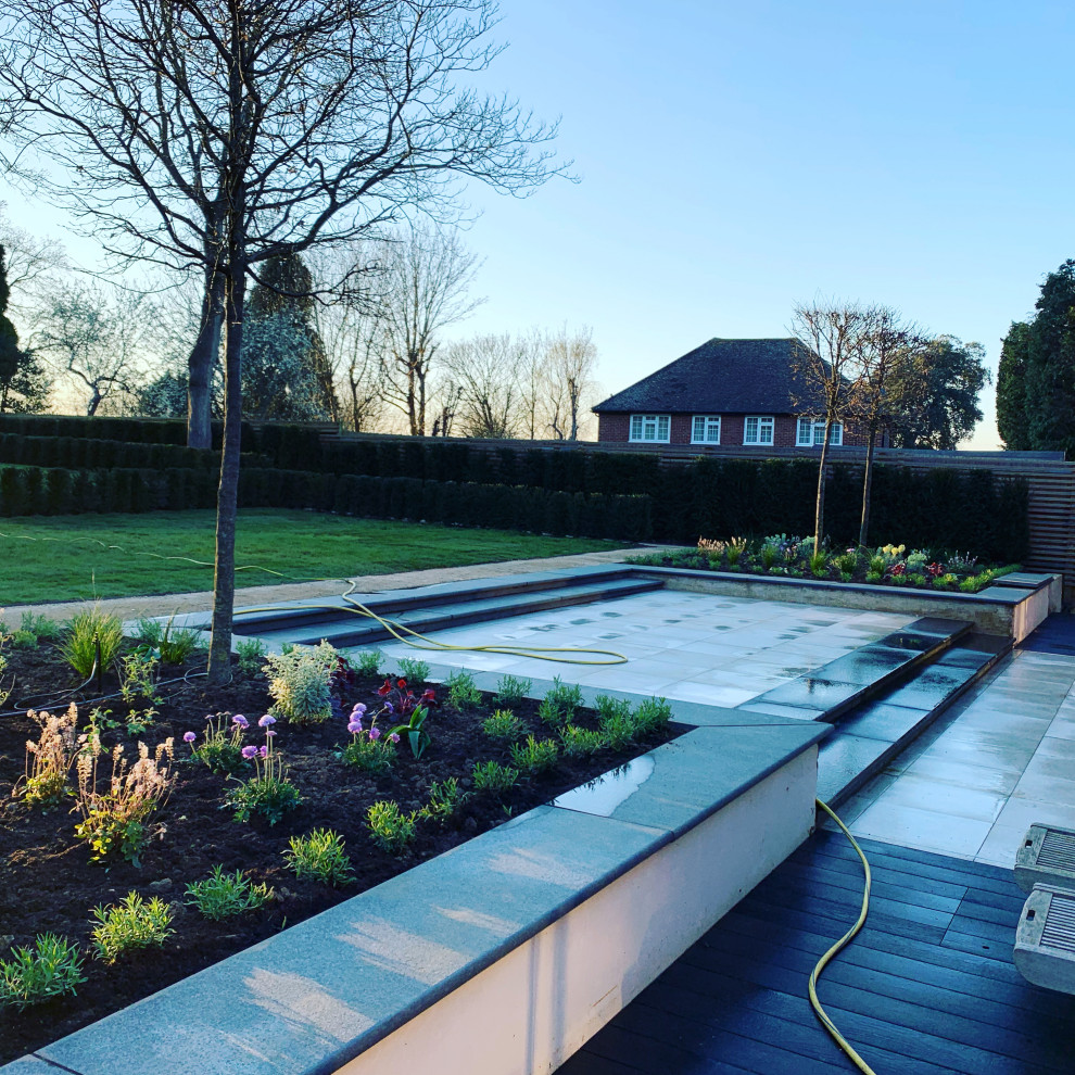 Medium sized modern back formal full sun garden for summer in Surrey with a flowerbed and concrete paving.