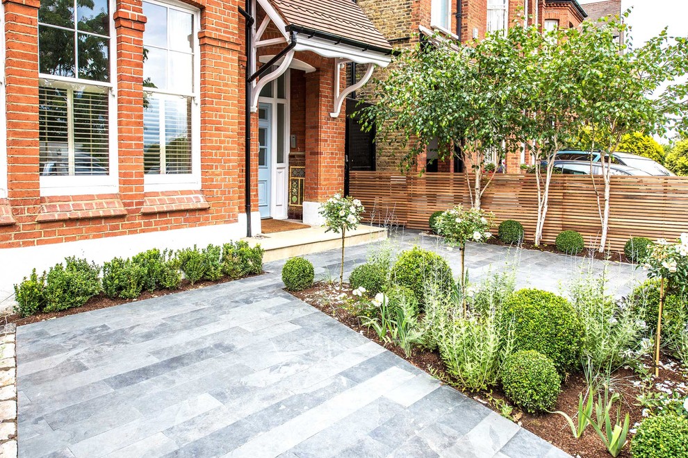 Photo of a contemporary front driveway garden in London with natural stone paving.