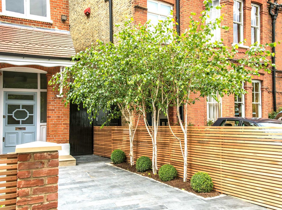 Contemporary front driveway garden in London with natural stone paving.