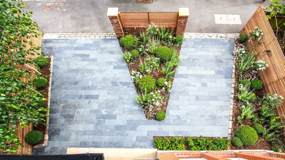 This is an example of a contemporary front driveway garden in London with natural stone paving.