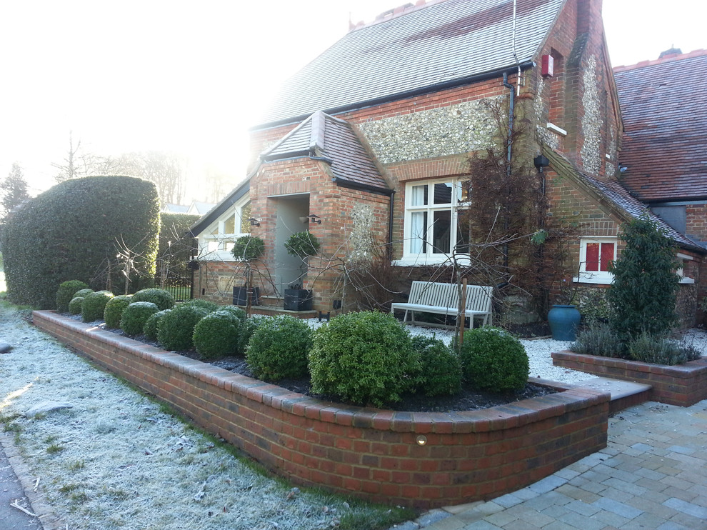 This is an example of a contemporary driveway fully shaded garden for winter in Cheshire with a garden path and brick paving.