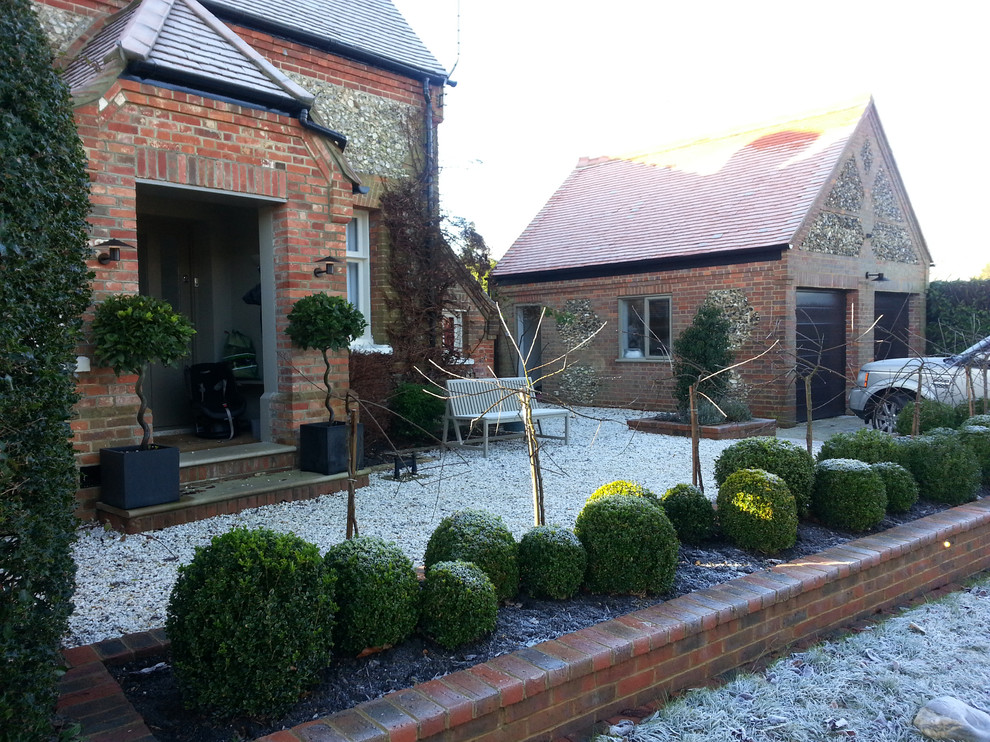 Small contemporary front driveway fully shaded garden for winter in Cheshire with a garden path and brick paving.