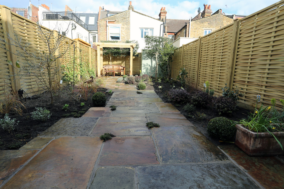 Modelo de jardín clásico de tamaño medio en patio trasero con exposición parcial al sol y adoquines de piedra natural