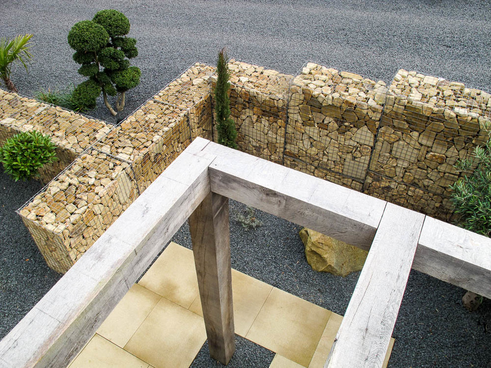 Aménagement d'un grand jardin à la française arrière contemporain avec un mur de soutènement et une terrasse en bois.