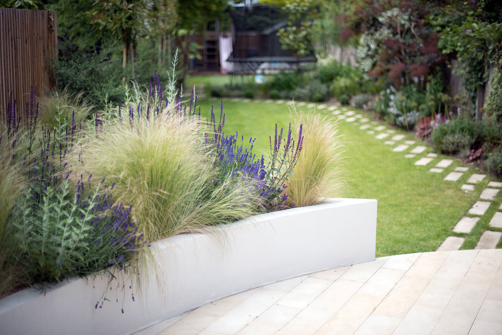 Medium sized contemporary back garden in London with natural stone paving.