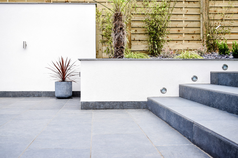 This is an example of a medium sized contemporary back full sun garden for summer in West Midlands with a retaining wall.