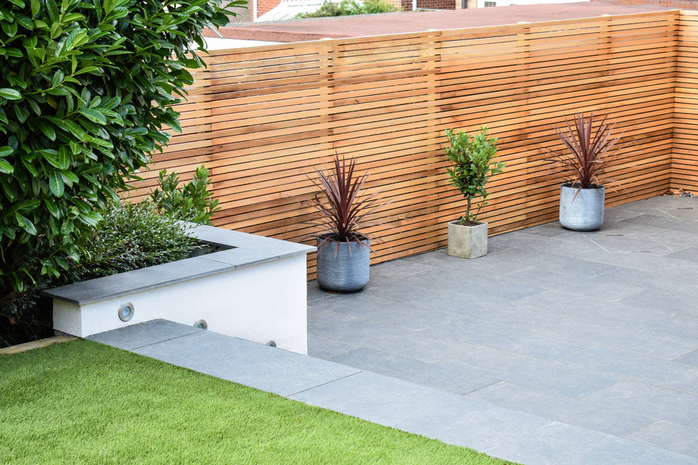 This is an example of a medium sized contemporary back full sun garden for summer in West Midlands with a retaining wall.