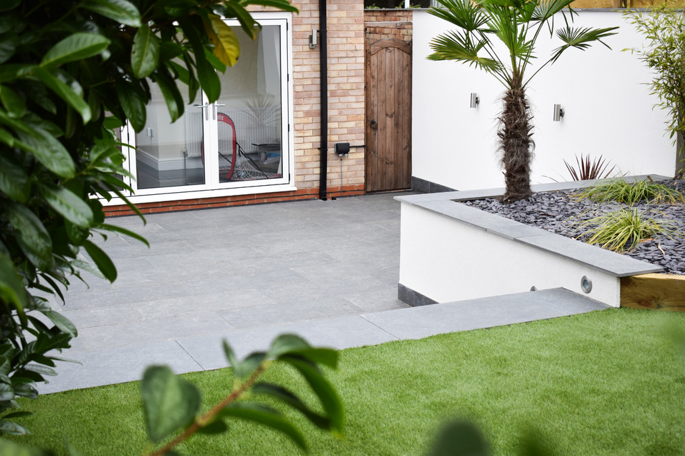 Esempio di un giardino minimal esposto in pieno sole di medie dimensioni e dietro casa in estate con un muro di contenimento