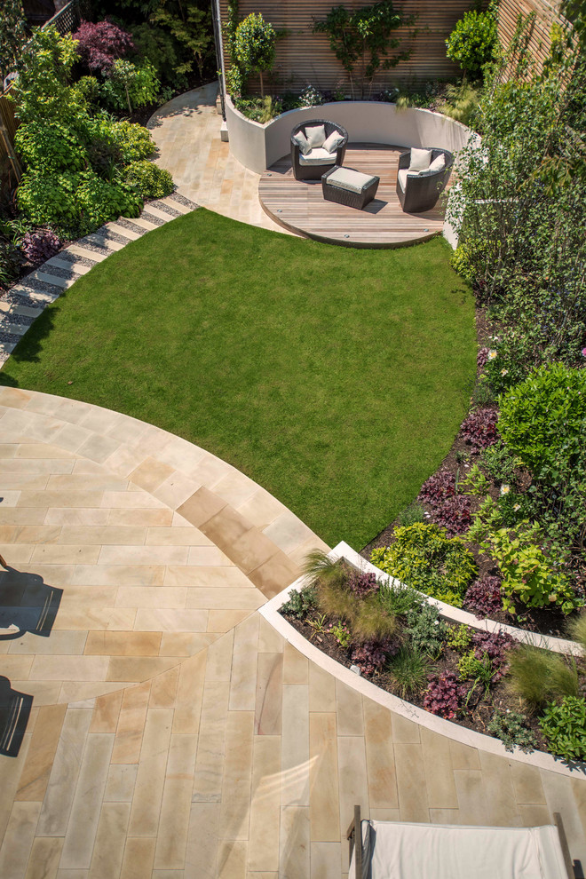 Cette image montre un jardin arrière design de taille moyenne avec une exposition ensoleillée et des pavés en pierre naturelle.