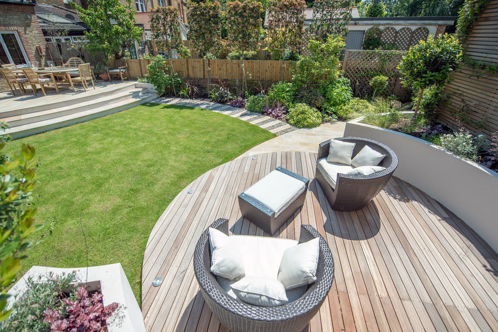 This is an example of a mid-sized contemporary full sun backyard garden path in London with decking.