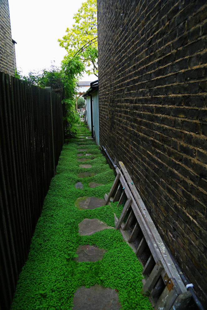 This is an example of a mid-sized traditional partial sun backyard stone formal garden in London for summer.