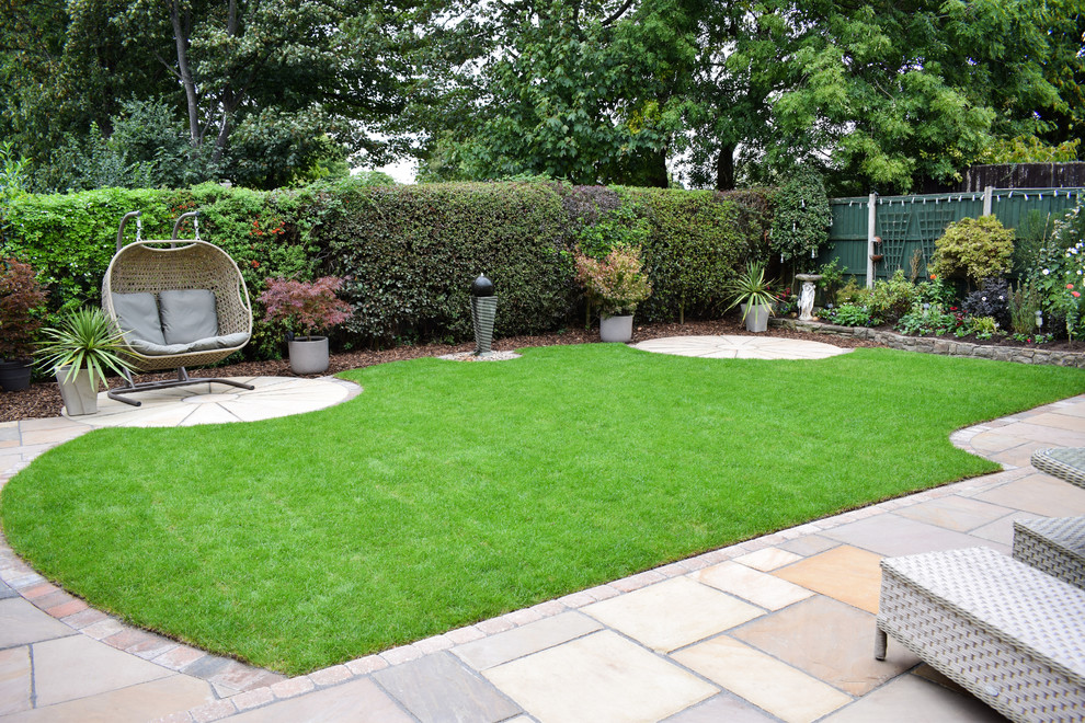 This is an example of a large classic back full sun garden for summer in West Midlands with a water feature and natural stone paving.