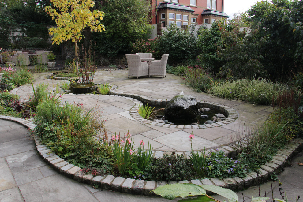This is an example of a classic back formal garden in Other with a pond and natural stone paving.