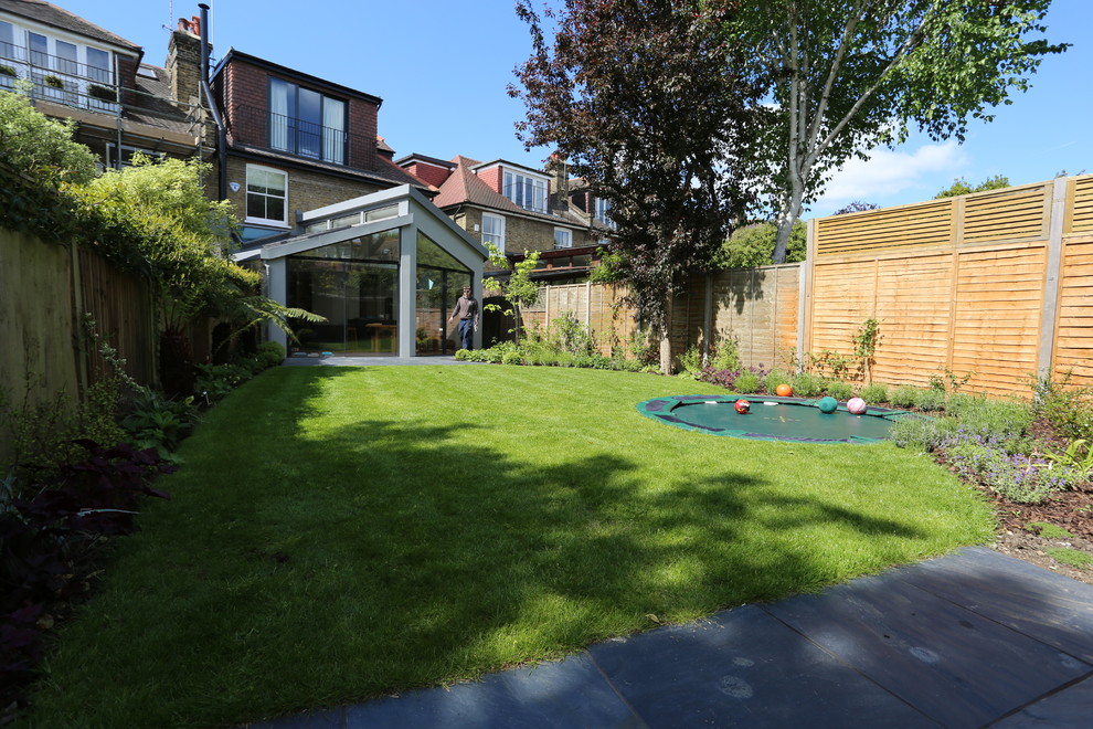 Inspiration for a mid-sized modern partial sun backyard stone formal garden in London.