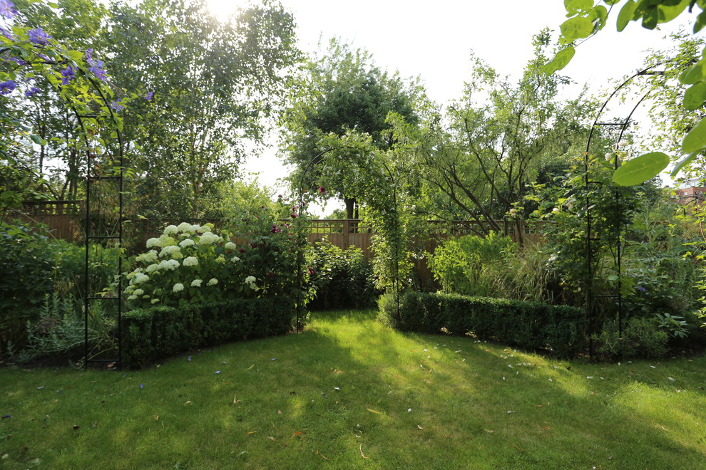 Ejemplo de jardín tradicional de tamaño medio en otoño en patio trasero con jardín francés, muro de contención, exposición total al sol y adoquines de ladrillo