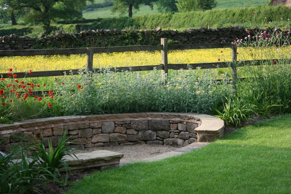 Foto de jardín de estilo de casa de campo de tamaño medio en verano en patio trasero con jardín francés, exposición total al sol y adoquines de piedra natural