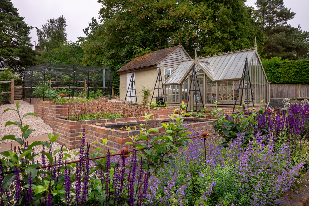 На фото: регулярный сад на заднем дворе в классическом стиле с растениями в контейнерах и покрытием из гравия