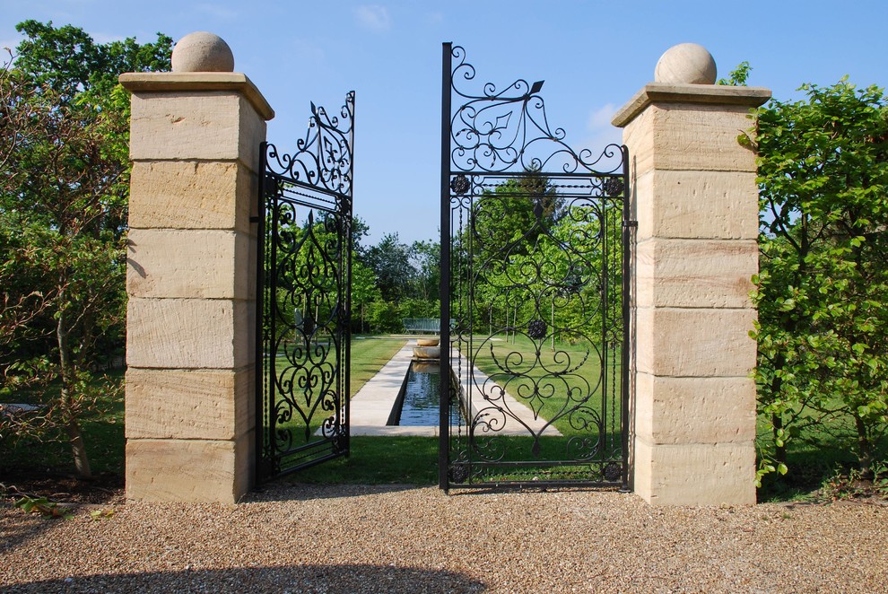 Exempel på en klassisk trädgård i full sol, med en fontän