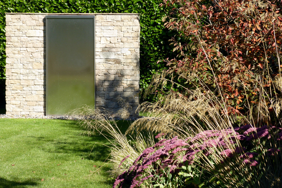 Medium sized contemporary back xeriscape full sun garden for summer in Hertfordshire with a water feature and mulch.