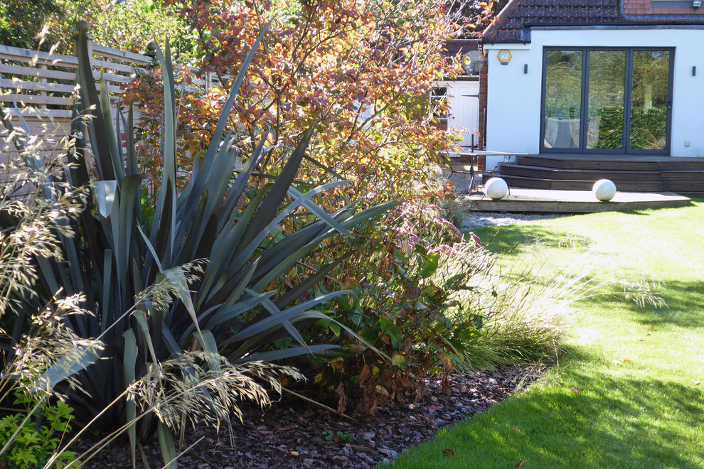 Medium sized contemporary back xeriscape full sun garden for summer in Hertfordshire with mulch.
