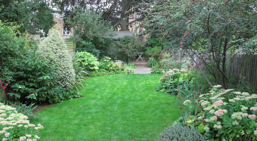 Diseño de jardín clásico grande en verano en patio trasero con exposición total al sol y entablado