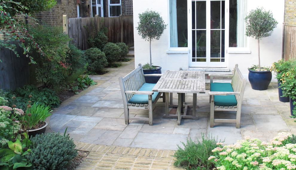 Large traditional back patio in London with brick paving.