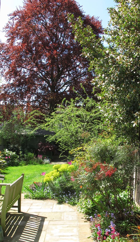 Exemple d'un jardin arrière chic de taille moyenne et au printemps avec une exposition ensoleillée et des pavés en pierre naturelle.