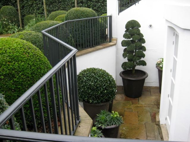 Contemporary front garden in Sussex with a potted garden and natural stone paving.