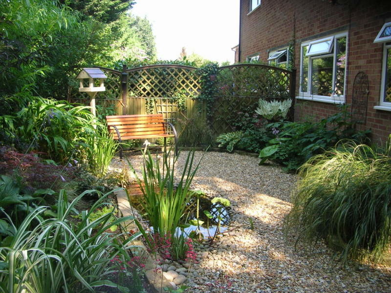 This is an example of a small traditional back fully shaded garden for summer in Surrey with a pond and gravel.