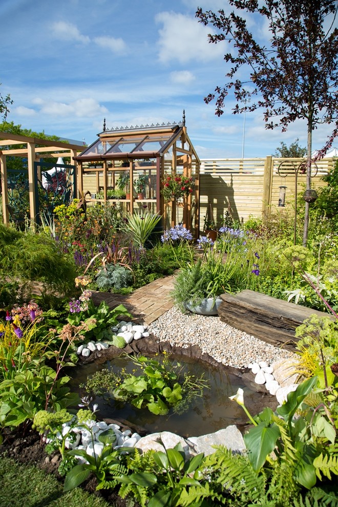 Modelo de jardín tradicional en verano en patio trasero con exposición total al sol, adoquines de piedra natural y fuente