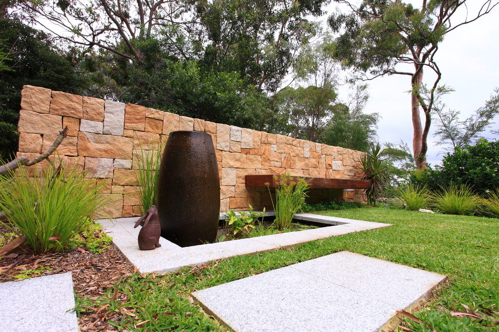 Photo of a small modern side partial sun garden in Sydney with a retaining wall and natural stone paving.