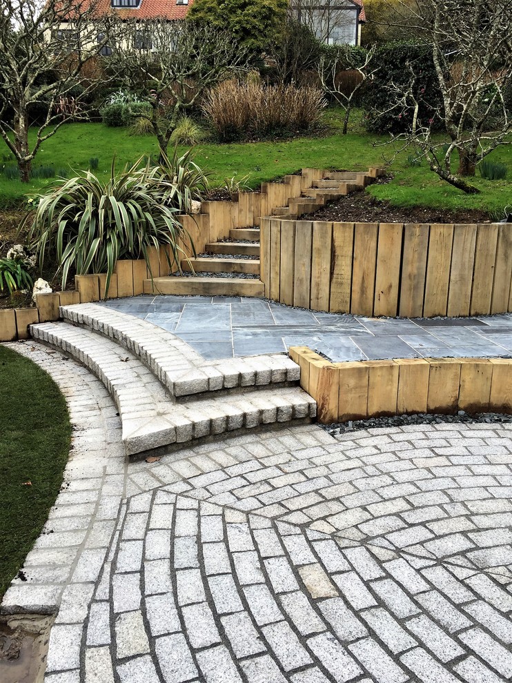 Inspiration for a large coastal back formal garden in Cornwall with a retaining wall and natural stone paving.