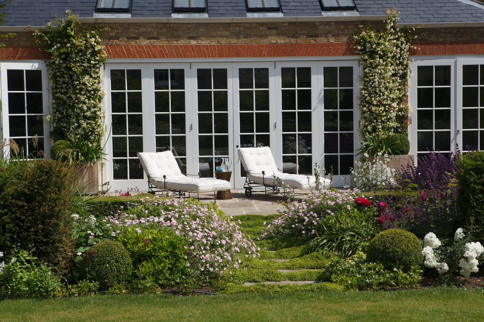 Exempel på en klassisk trädgård i full sol, med en trädgårdsgång