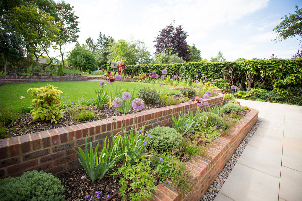 На фото: большой солнечный регулярный сад на склоне в классическом стиле с хорошей освещенностью и мощением клинкерной брусчаткой